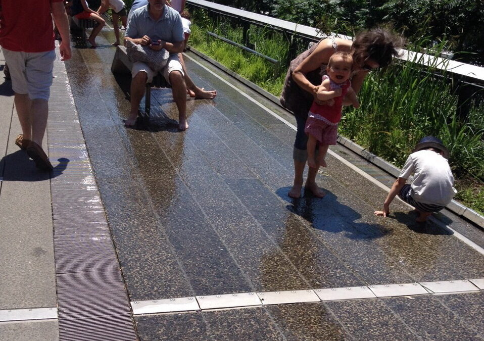 No calor, os visitantes curtem os pisos com água no High Line Parque em Nova Iorque